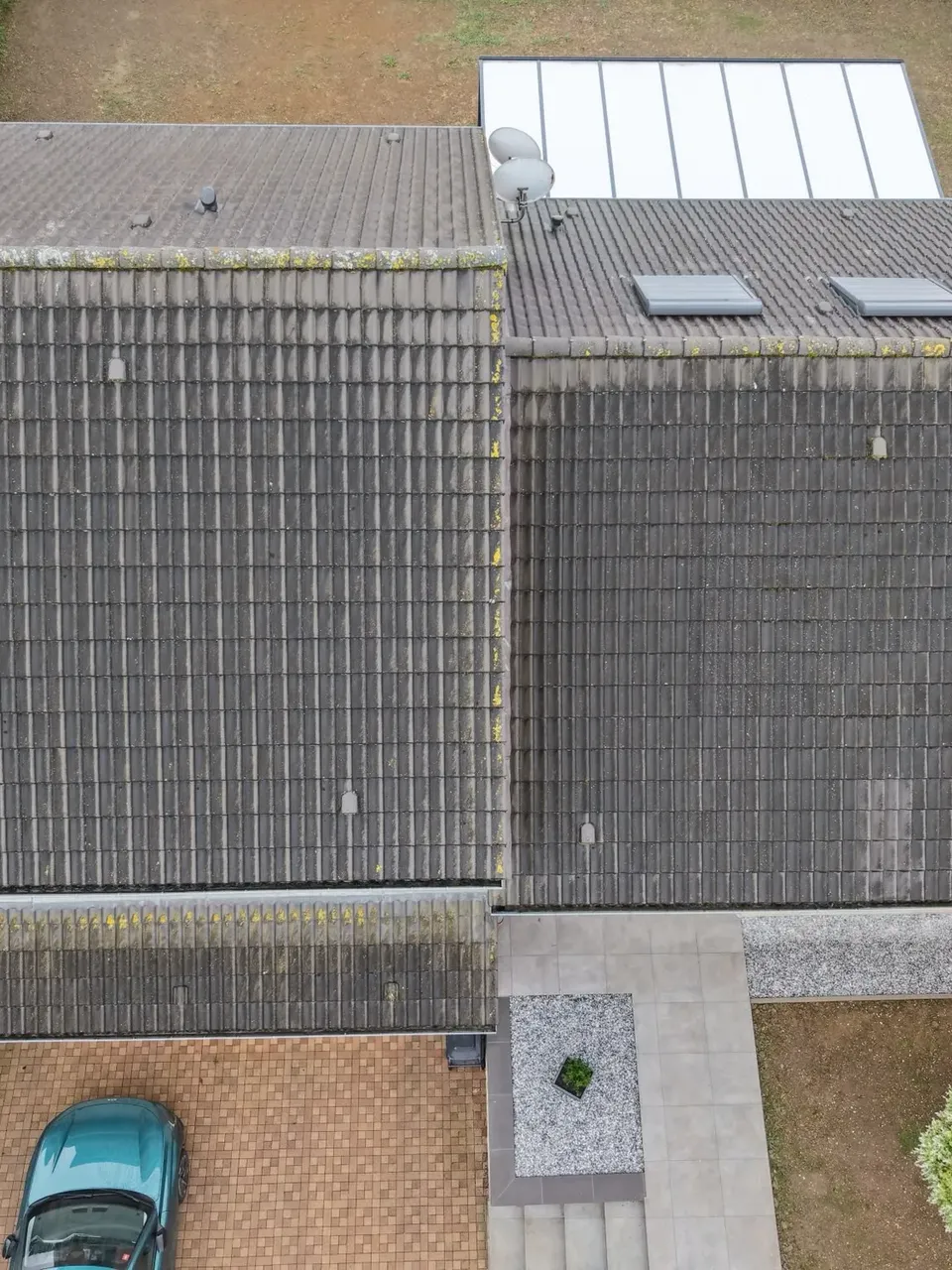 Vue aérienne par drone d'une toiture en tuiles sombres envahie par la mousse et le lichen à Boulange - Drone Net Services